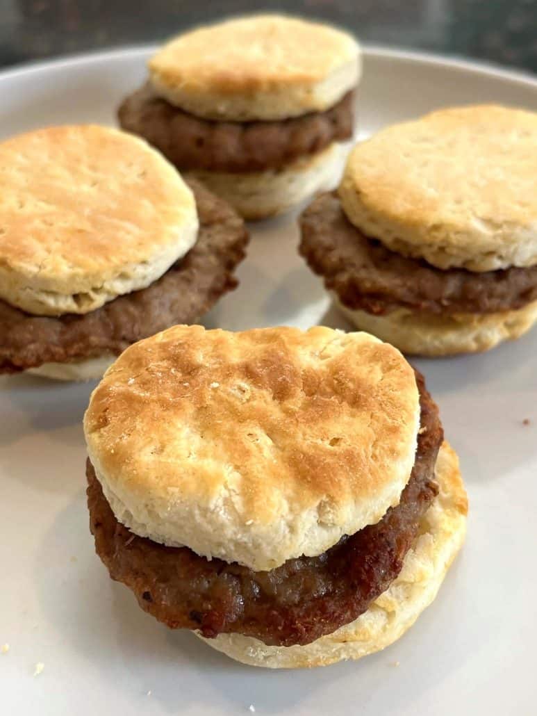 Close-up of four cooked Jimmy Dean Biscuit Sausage Sandwiches on a plate, showcasing their golden biscuits and savory sausage filling.