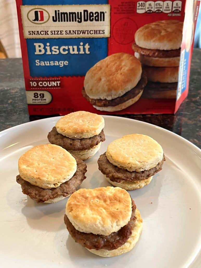 Plate of freshly cooked Jimmy Dean Biscuit Sausage Sandwiches in front of their packaging.