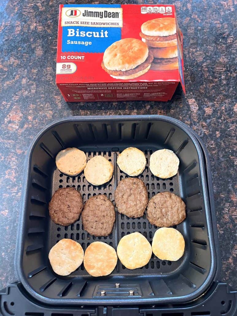 Jimmy Dean Biscuit Sausage Snack Sandwiches box next to an air fryer basket with separated biscuit halves and sausage patties, ready for air frying.