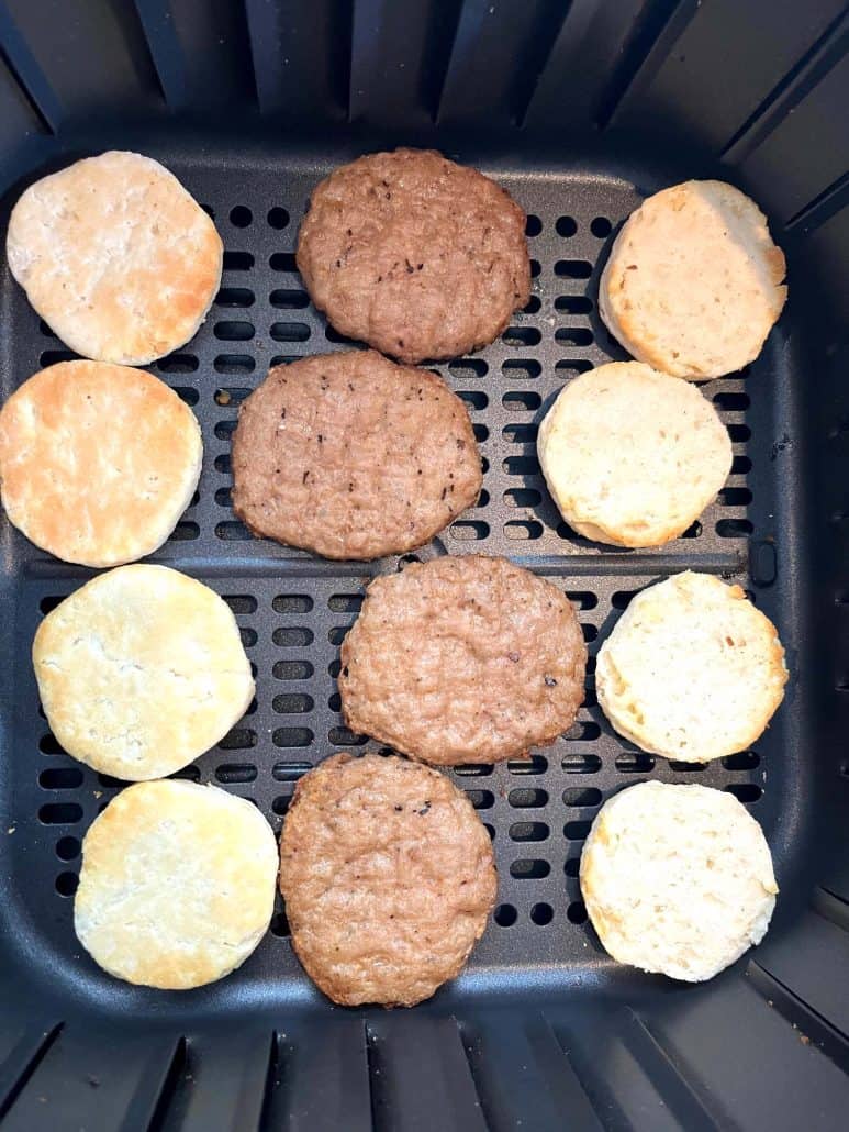 Top-down view of an air fryer basket with biscuit halves and sausage patties spaced out for even cooking in the Jimmy Dean Biscuit Sausage Sandwich recipe.