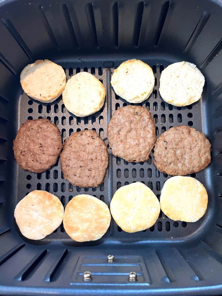 Air fryer basket with sausage patties and biscuit halves evenly spaced, showing the preparation step for Jimmy Dean Biscuit Sausage Sandwiches.