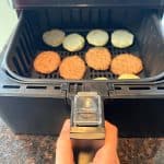 Air fryer basket with separated sausage patties and biscuit halves, illustrating the preparation step for cooking Jimmy Dean Biscuit Sausage Sandwiches in the air fryer.