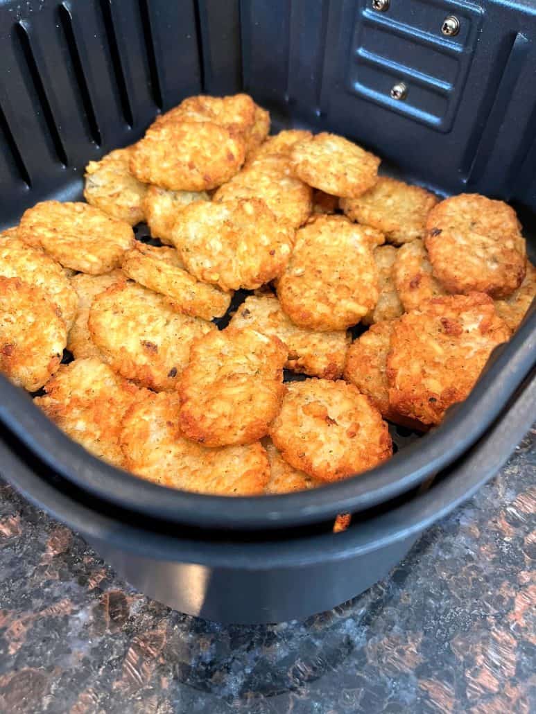 Side view of crispy, golden McCain Baby Cakes Hashbrowns freshly cooked and sitting in the air fryer basket, showcasing their texture.