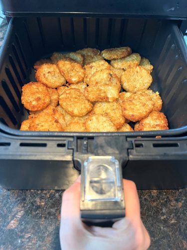 Golden and crispy McCain Baby Cakes Hashbrowns freshly cooked in an air fryer basket, showing their perfect texture and doneness.