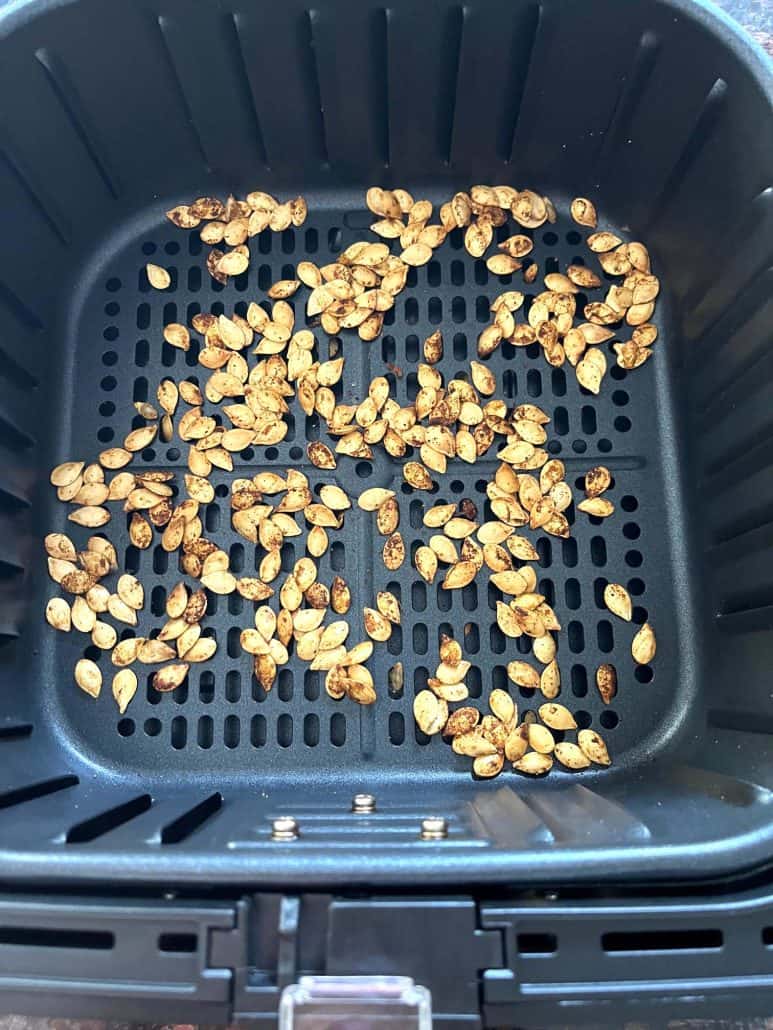 Air fryer basket showcasing a batch of golden, evenly roasted pumpkin seeds, ready to enjoy as a crunchy snack.