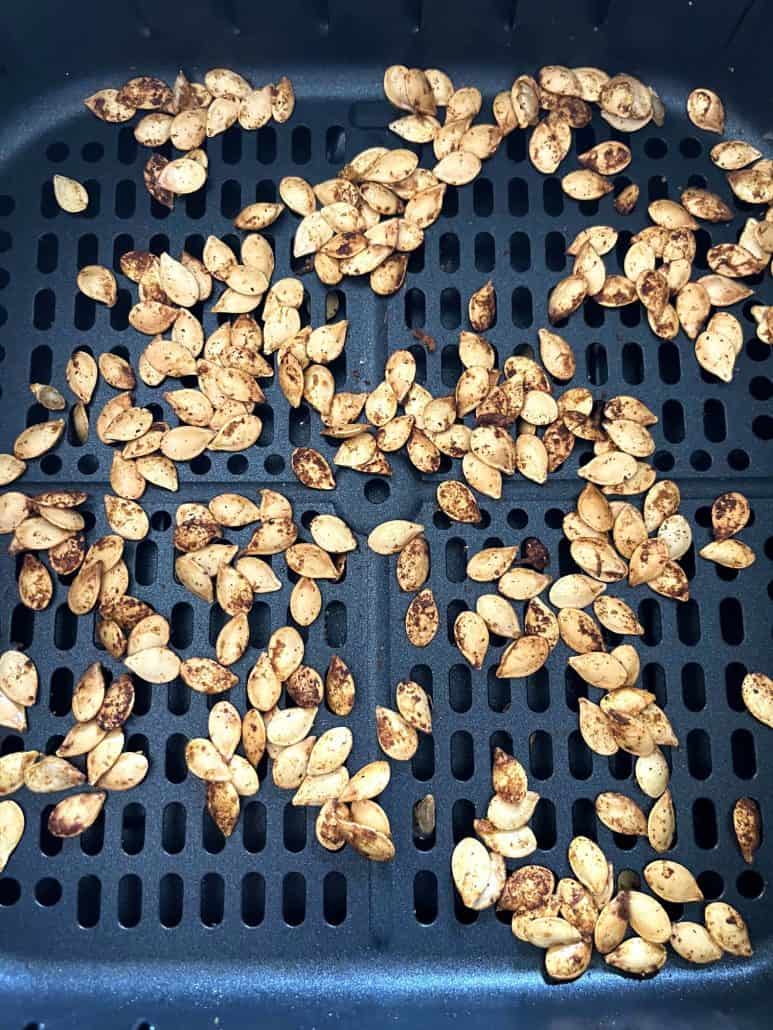 Close-up view of perfectly roasted pumpkin seeds in an air fryer basket, golden brown and ready to enjoy as a crunchy, nutritious snack.