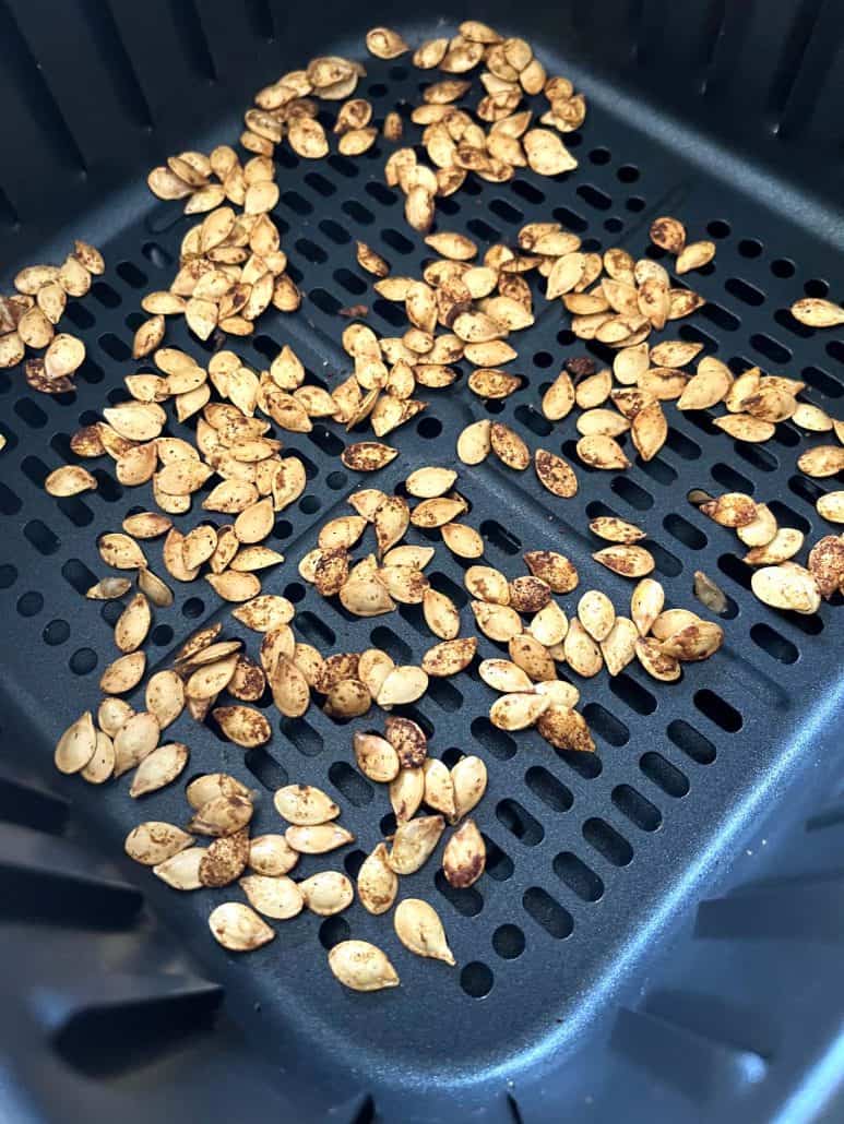 Close-up of golden, crispy pumpkin seeds roasted to perfection in an air fryer basket.