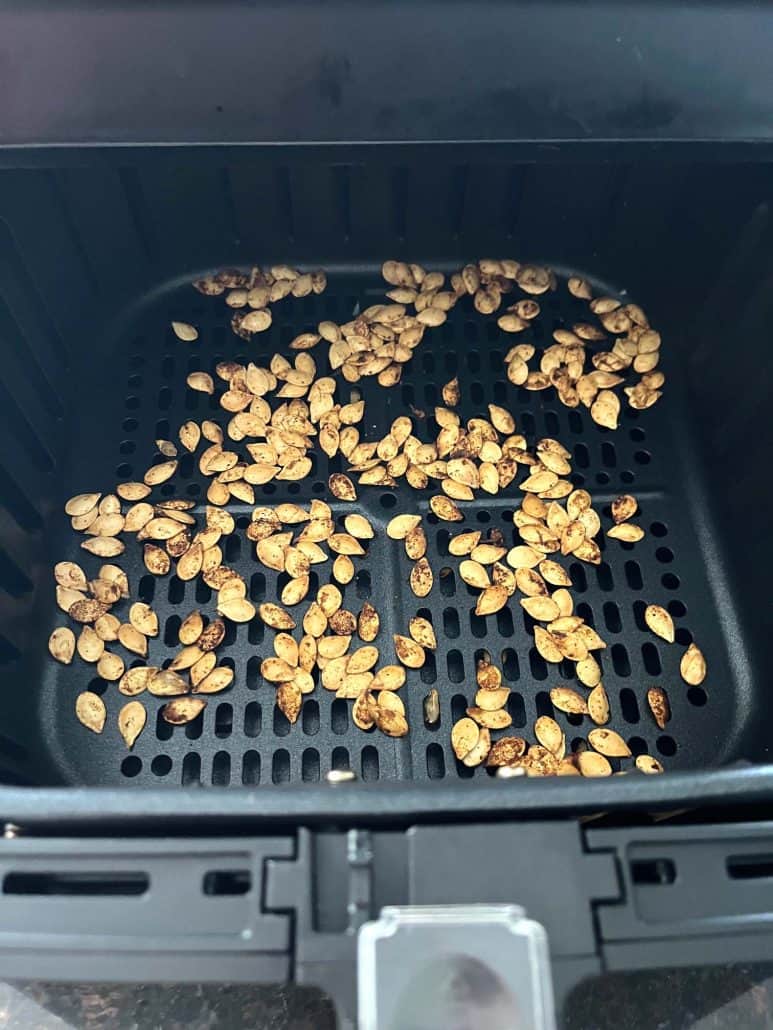 Air fryer basket filled with evenly roasted pumpkin seeds.