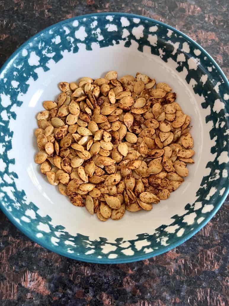 Bowl filled with golden, roasted pumpkin seeds, ready to be enjoyed as a crunchy.