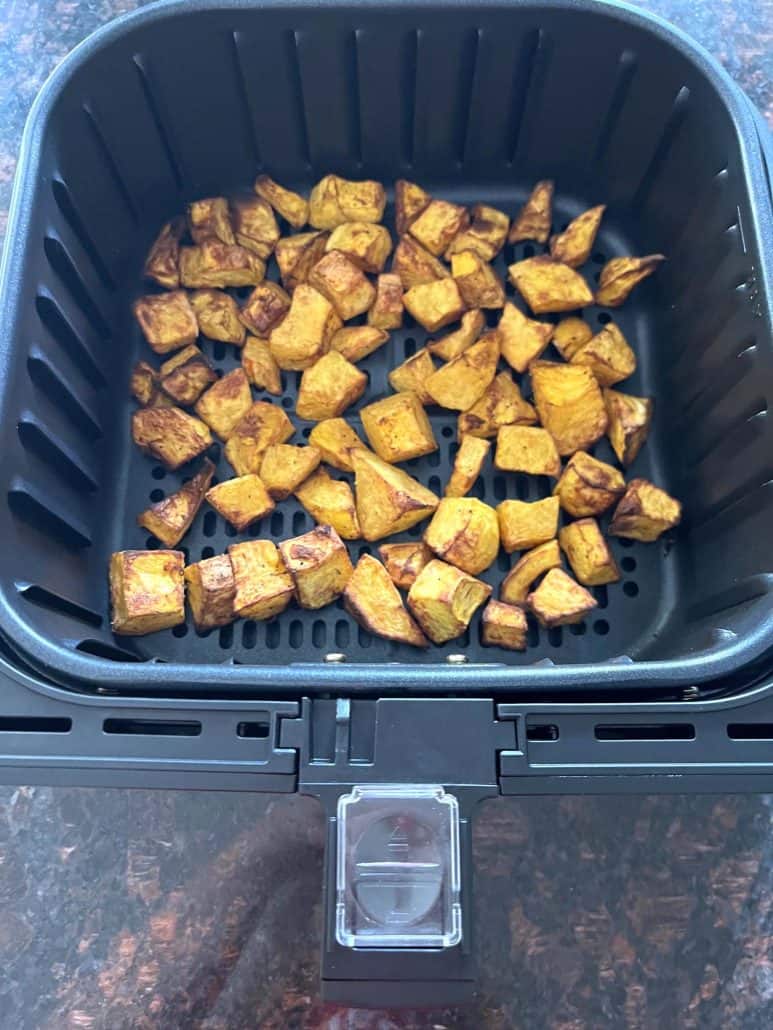 Top view of roasted pumpkin cubes in the air fryer basket.