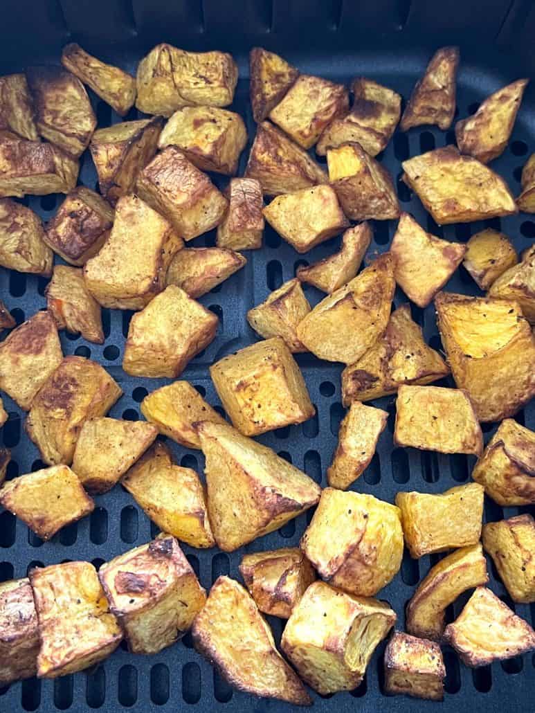 Close-up of roasted pumpkin, highlighting their crispy texture in an air fryer basket.