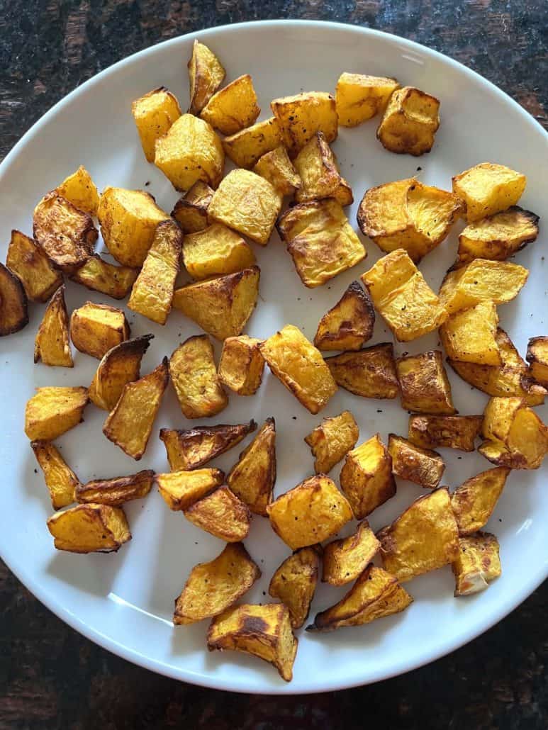 Golden, crispy air-fried pumpkin cubes served on a white plate.