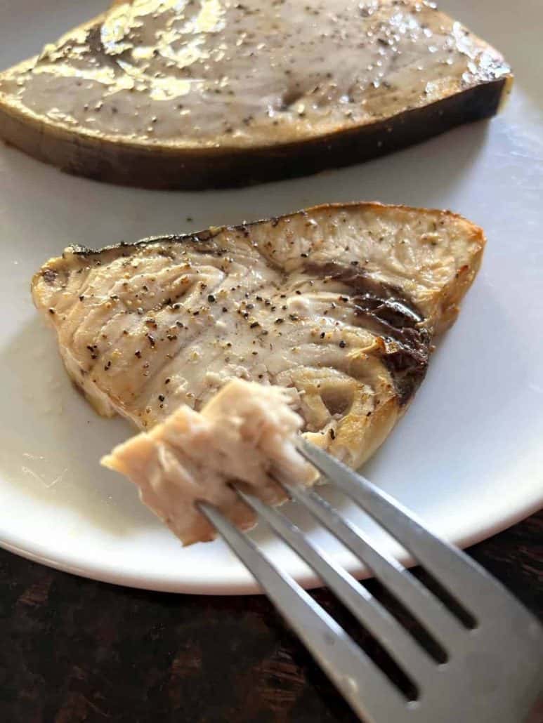 Close-up of a fork holding a flaky bite of air-fried swordfish.