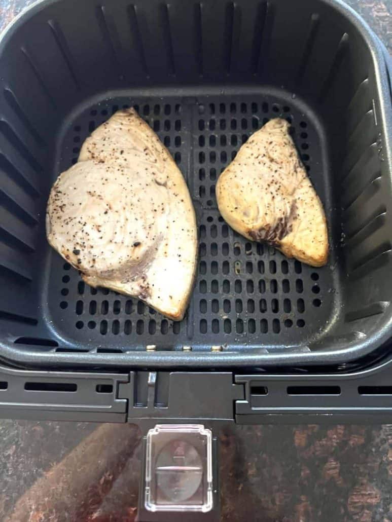 Two seasoned swordfish fillets placed in an air fryer basket, showcasing a simple method to cook fish to tender perfection.