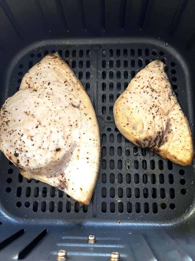 Two swordfish fillets in an air fryer basket, a healthy seafood meal.