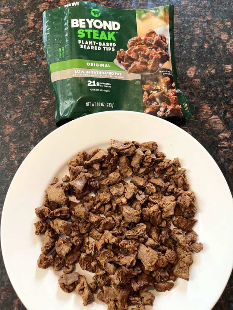 Cooked Beyond Steak Tips served on a white plate with the original packaging in the background, showcasing a delicious and easy vegan meal option.