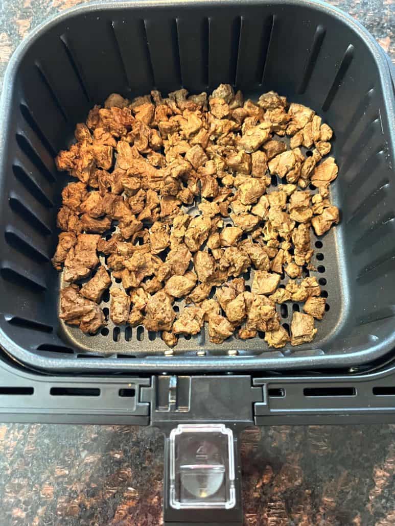 Golden-brown cooked Beyond Steak Tips in an air fryer basket, showcasing their crispy and appetizing texture.