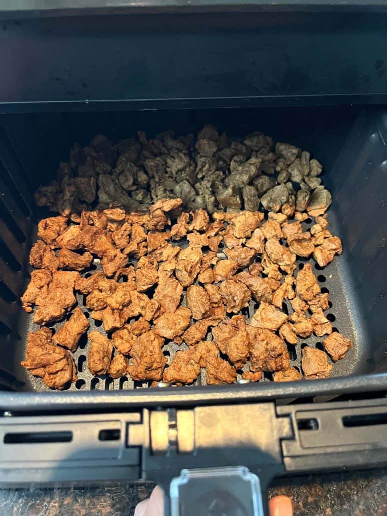 Cooked Beyond Steak Tips in an air fryer basket, perfectly browned and ready to serve.