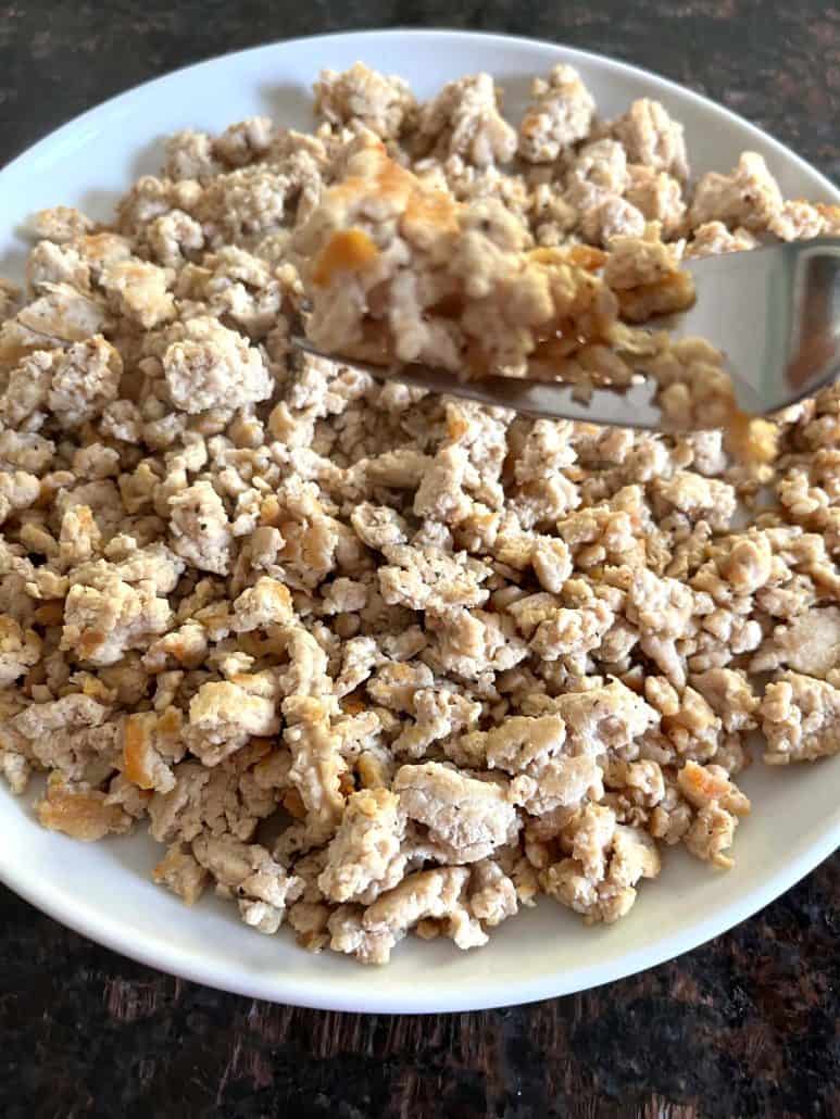 Plate of freshly cooked ground chicken with a fork, ideal for meal prep or incorporating into a variety of dishes.