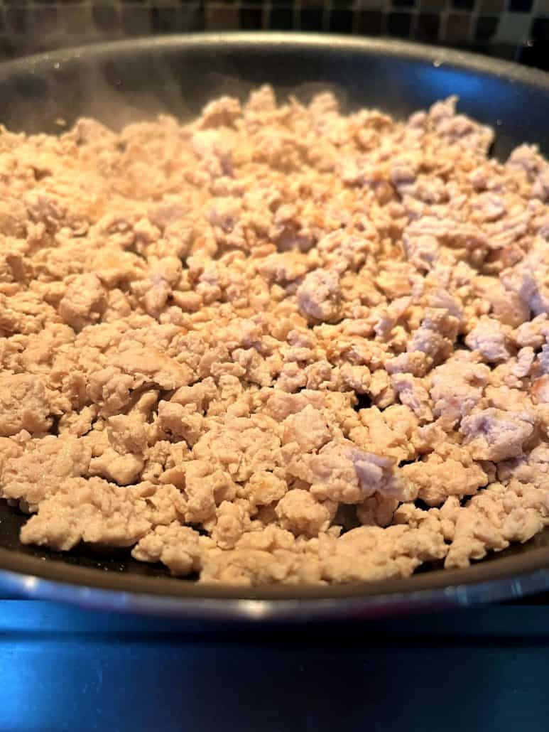 Close-up of ground chicken cooking in a frying pan.