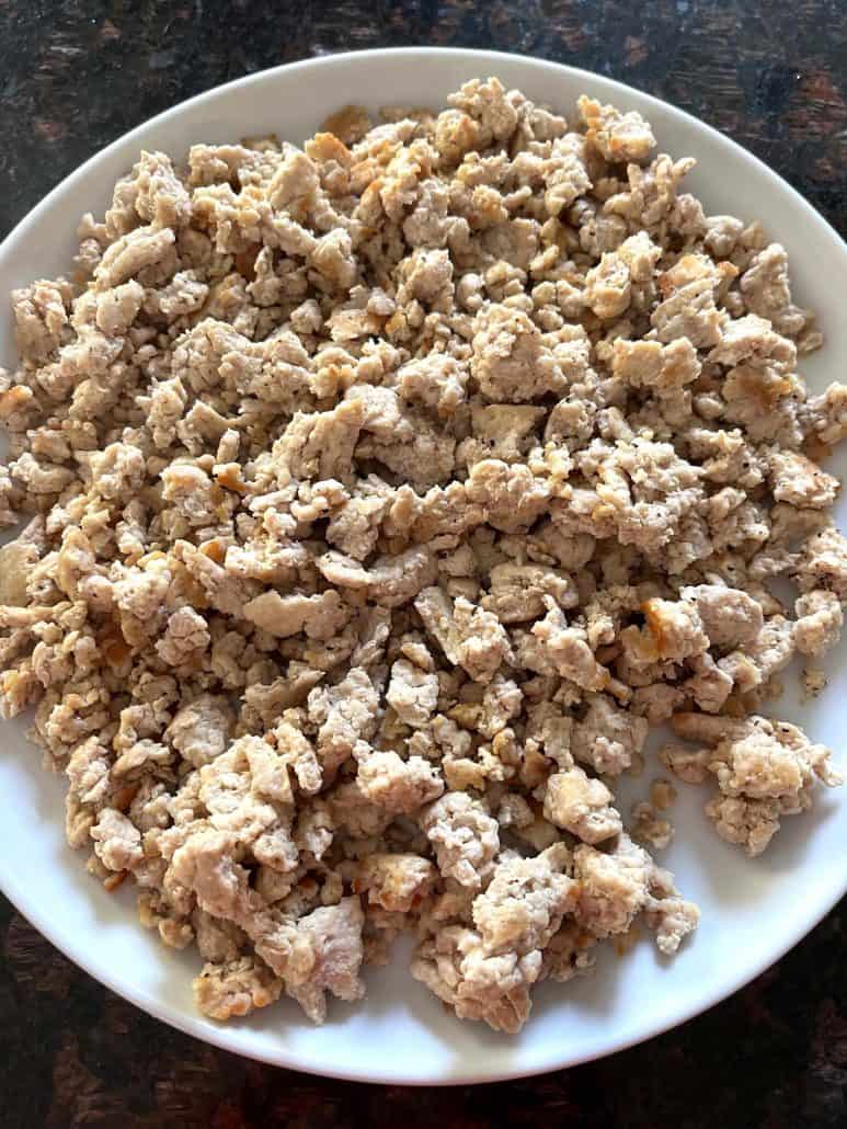 Plate of fully cooked ground chicken, ready to be used in various recipes or served as a protein-rich meal component.