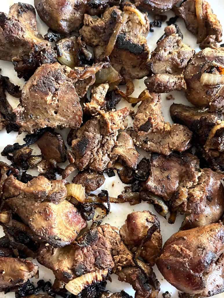 Close-up of pan-fried chicken livers with caramelized onions, showcasing the rich, golden-brown texture and savory seasoning.