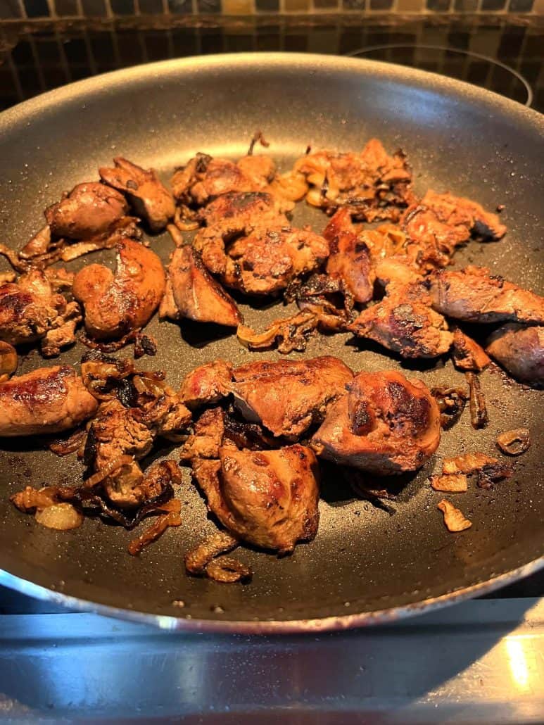 Pan-fried chicken livers with golden-brown caramelization, ready to be served as a hearty dish with onions.