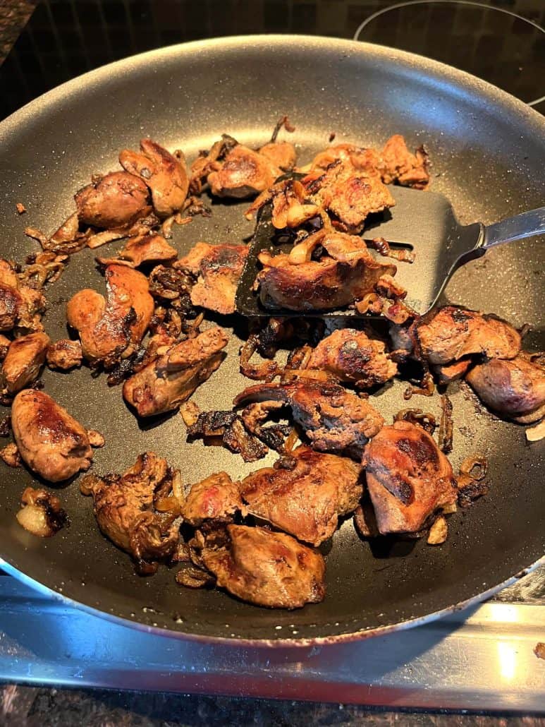 Pan-fried chicken livers in a skillet, cooked until browned.