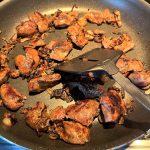 Pan-fried chicken livers cooking in a skillet, browned to perfection for a simple and flavorful dish with caramelized onions.