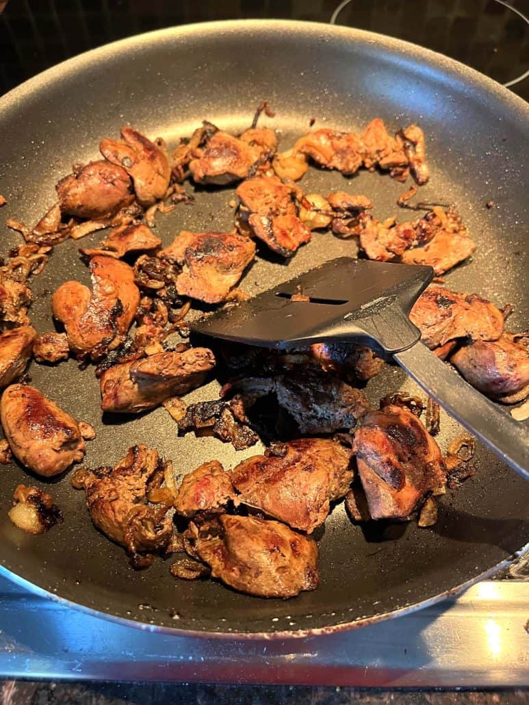 Pan-fried chicken livers cooking in a skillet, browned to perfection for a simple and flavorful dish with caramelized onions.