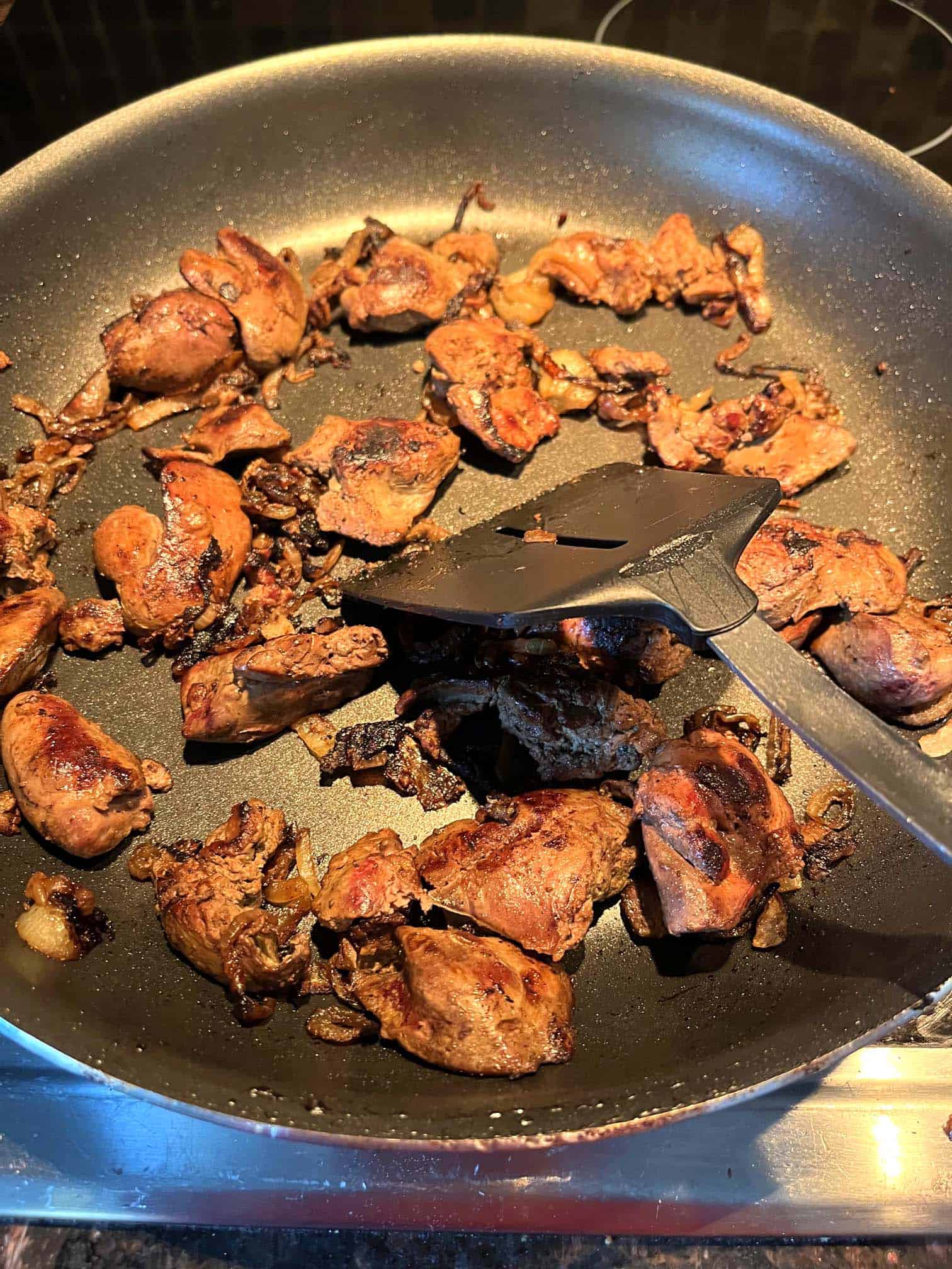 Pan-fried chicken livers cooking in a skillet, browned to perfection for a simple and flavorful dish with caramelized onions.