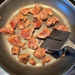 Sauteed chicken livers being cooked in a non-stick pan with a spatula, showing the browning process for a quick and easy recipe.