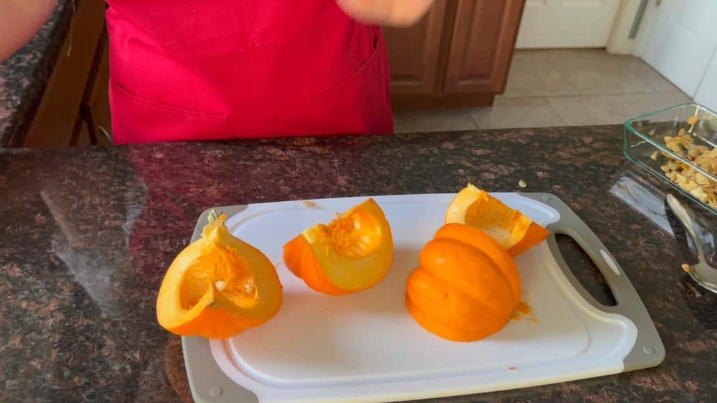 Pumpkin cut into quarters on a cutting board, ready for peeling and further preparation