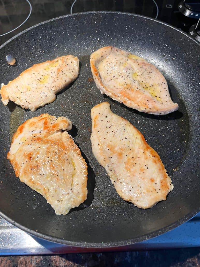 Golden-brown chicken breasts sizzling in a non-stick pan.