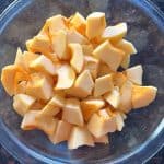 Glass bowl filled with freshly cubed pumpkin pieces, ready for cooking or storing.