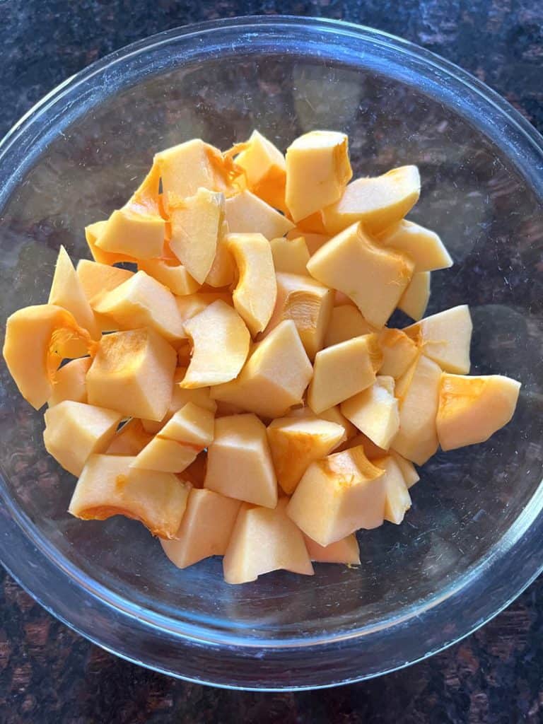 Glass bowl filled with freshly cubed pumpkin pieces, ready for cooking or storing.