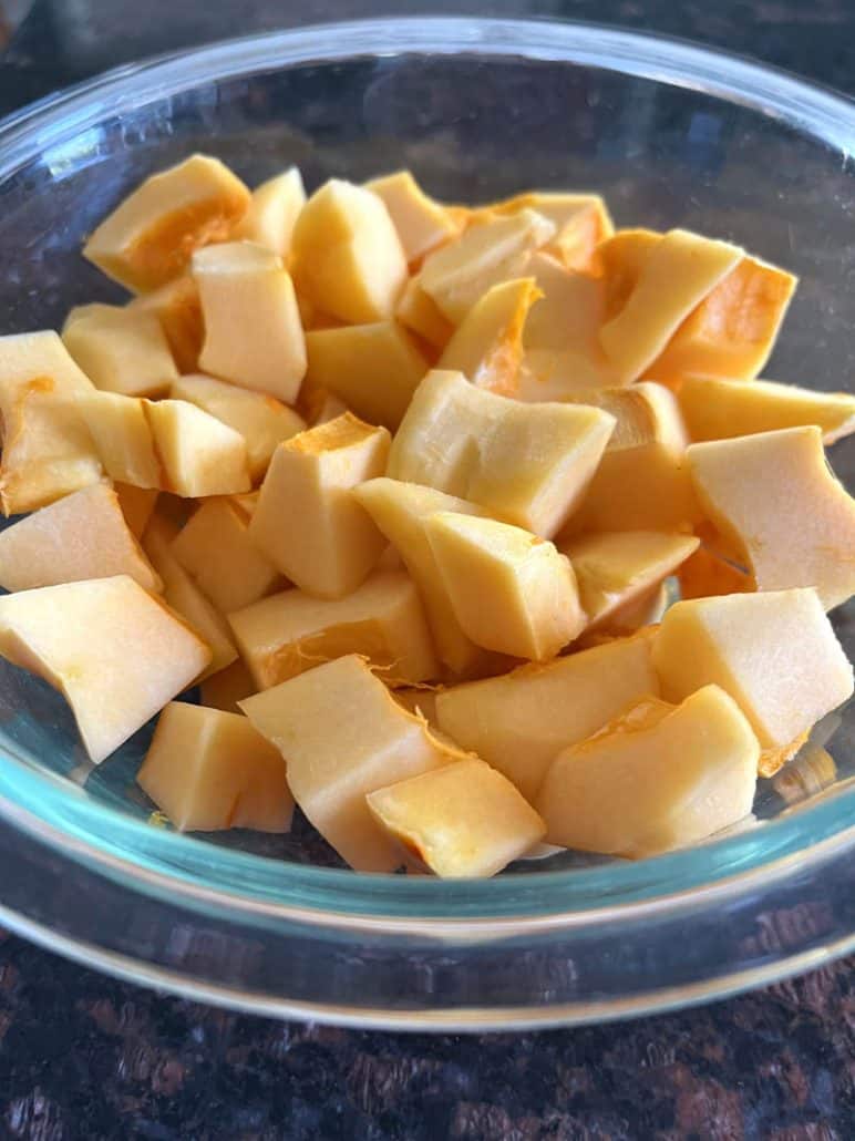 Freshly cubed pumpkin pieces in a glass bowl, prepped and ready for cooking or roasting.