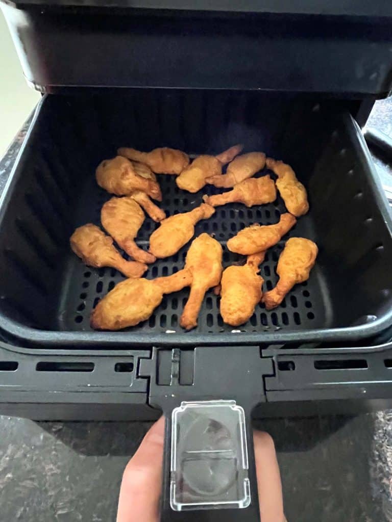 Air fryer basket filled with golden, crispy beer-battered shrimp, freshly cooked and ready to serve, highlighting their crunchy texture and quick preparation.