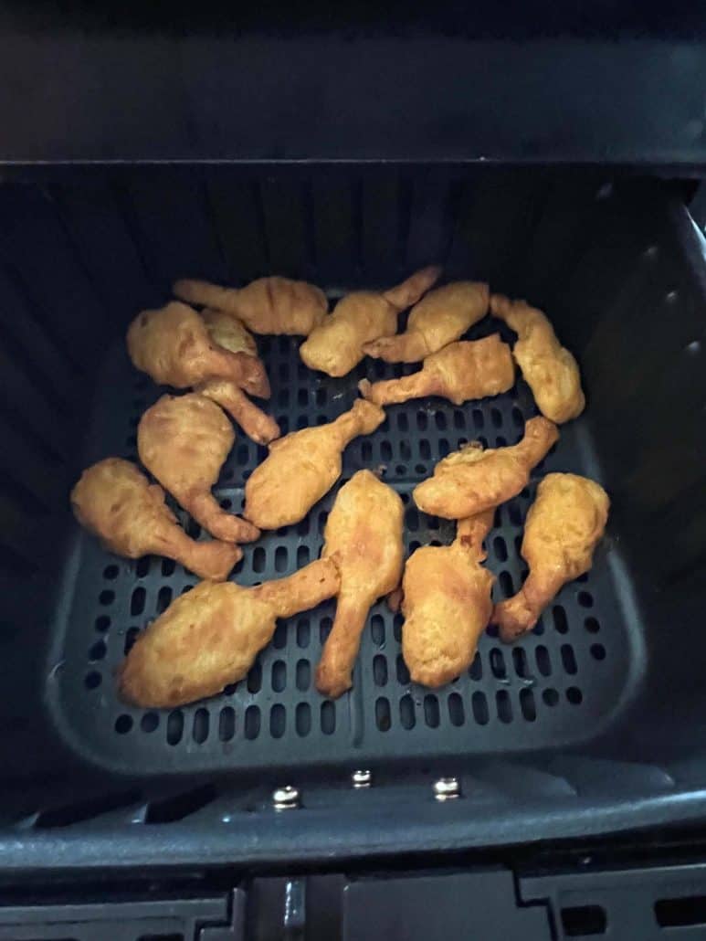 Close-up of golden, crispy beer-battered shrimp arranged inside an air fryer basket, showcasing their even cooking and crunchy texture.