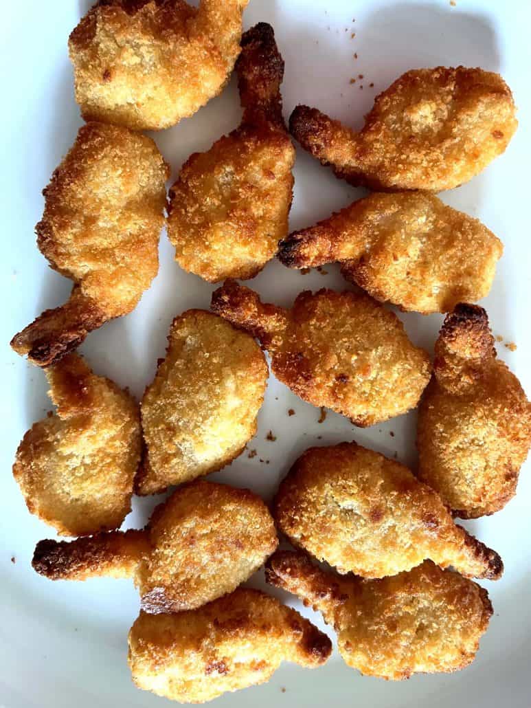 Close-up of a plate filled with golden, crispy butterfly shrimp arranged neatly and ready to serve.