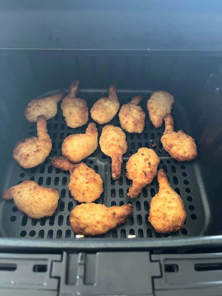 Golden brown butterfly shrimp perfectly cooked in the air fryer basket.