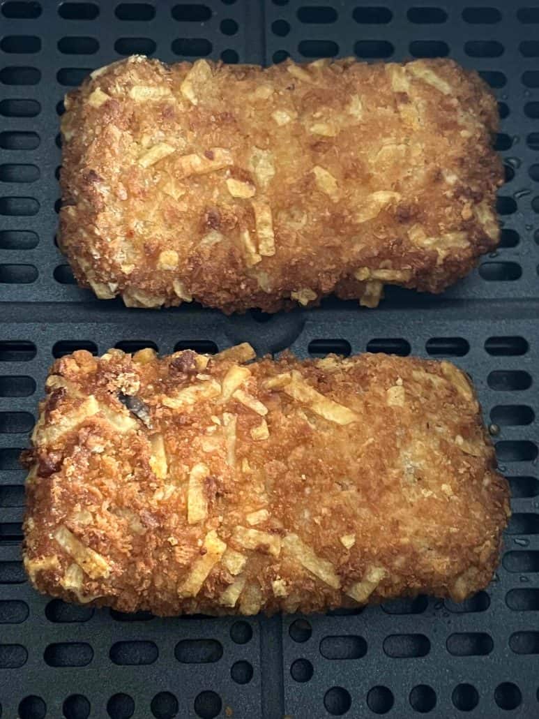 Top-down close-up of two perfectly crispy Jimmy Dean stuffed hashbrowns in an air fryer basket, showcasing their golden texture.