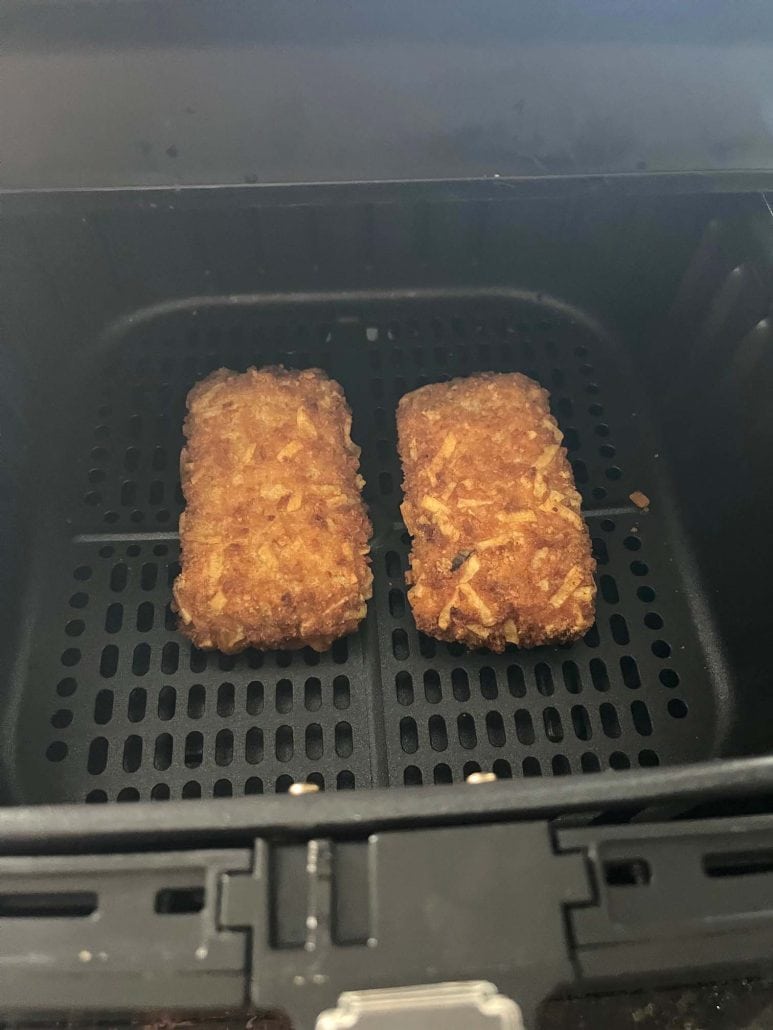 Two crispy Jimmy Dean stuffed hashbrowns in an air fryer basket, perfectly cooked and golden brown.