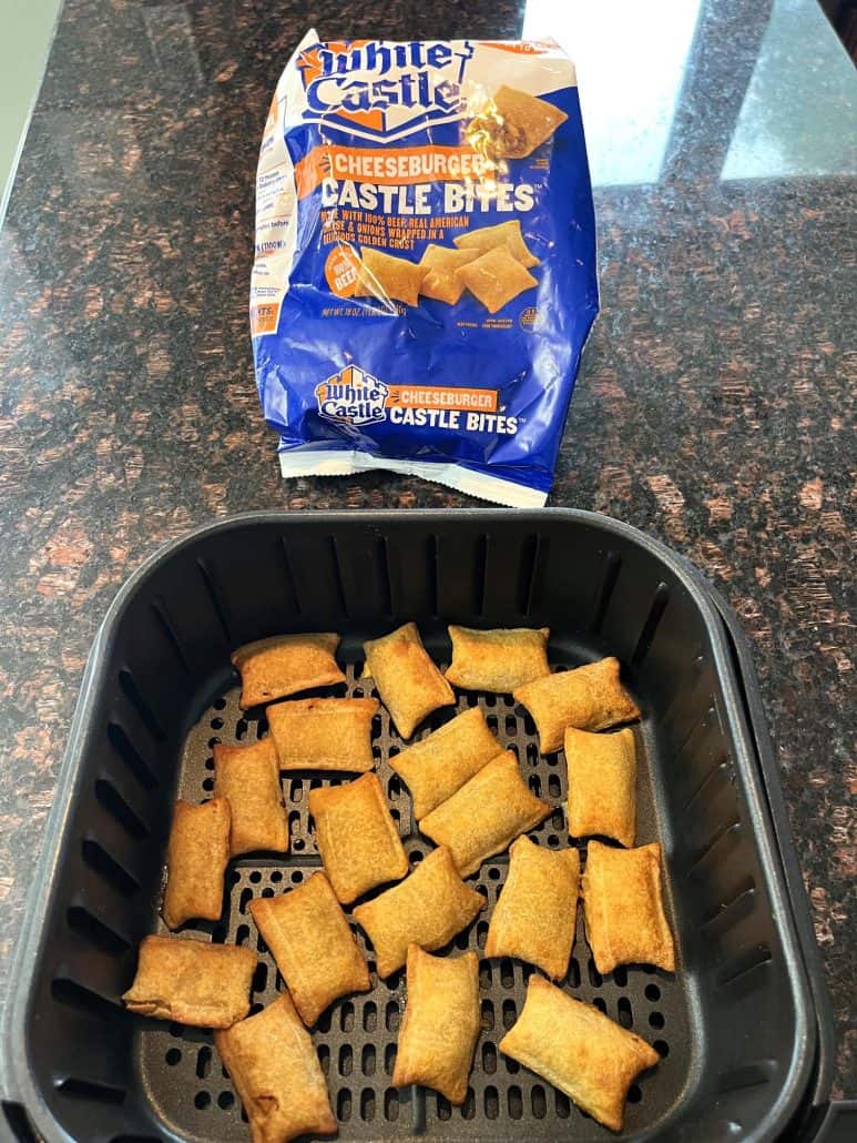 Air fryer basket filled with crispy, golden-brown White Castle Cheeseburger Bites, positioned in front of the branded package, emphasizing their texture and convenience as a quick and tasty snack option.