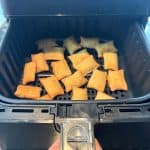 Close-up of an air fryer basket being held open, filled with crispy, golden-brown White Castle Cheeseburger Bites, highlighting their perfectly cooked texture for a quick and easy snack or meal.