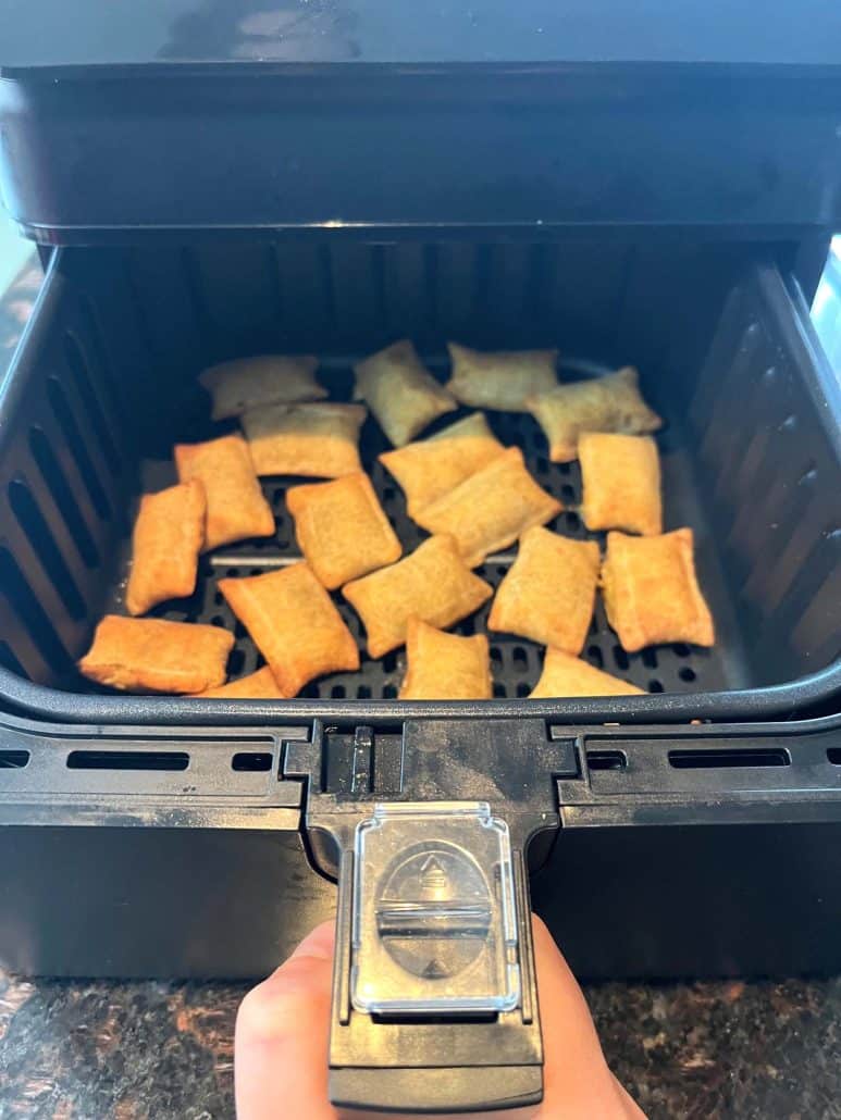 Close-up of an air fryer basket being held open, filled with crispy, golden-brown White Castle Cheeseburger Bites, highlighting their perfectly cooked texture for a quick and easy snack or meal.