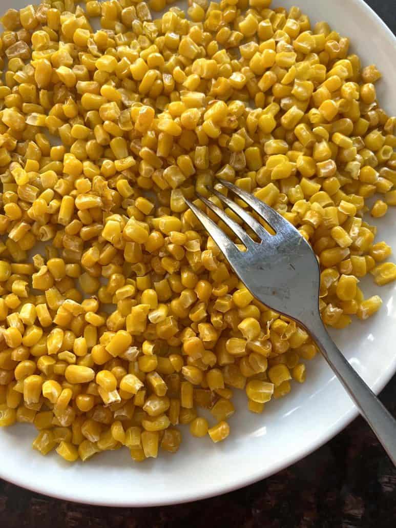 Plate of crispy air fryer corn with a fork resting on the side, ready to serve.