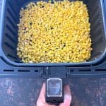 Cooked frozen corn in an air fryer basket, showing the crispy, golden result of this easy air fryer frozen corn recipe.