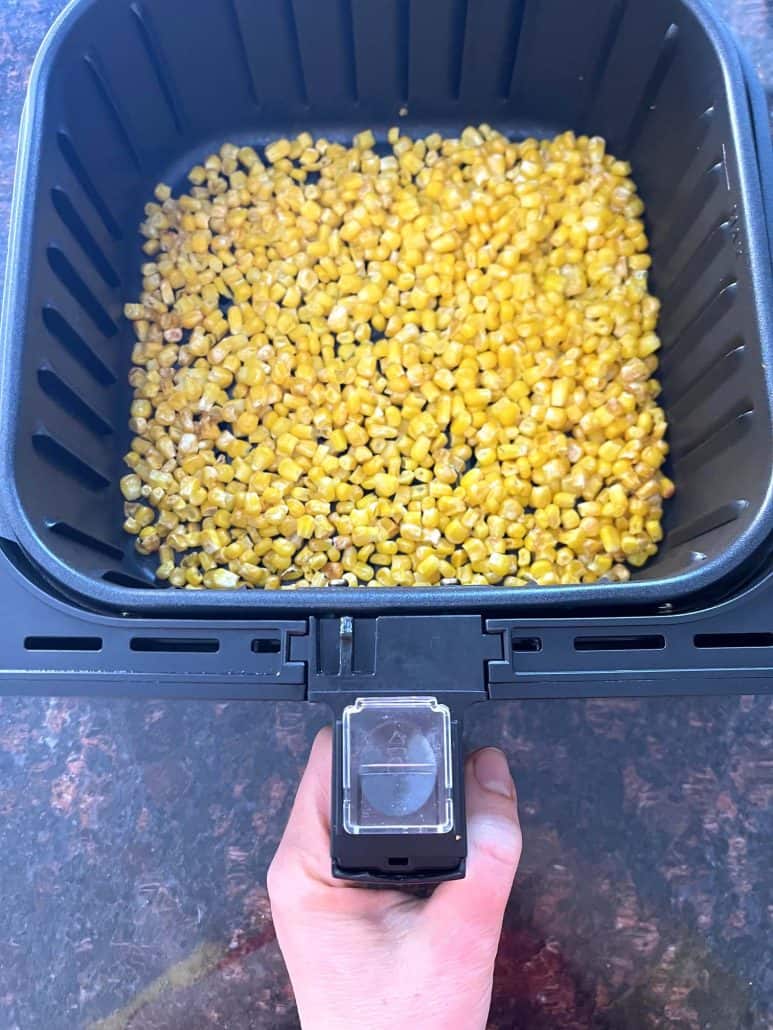 Cooked frozen corn in an air fryer basket, showing the crispy, golden result of this easy air fryer frozen corn recipe.