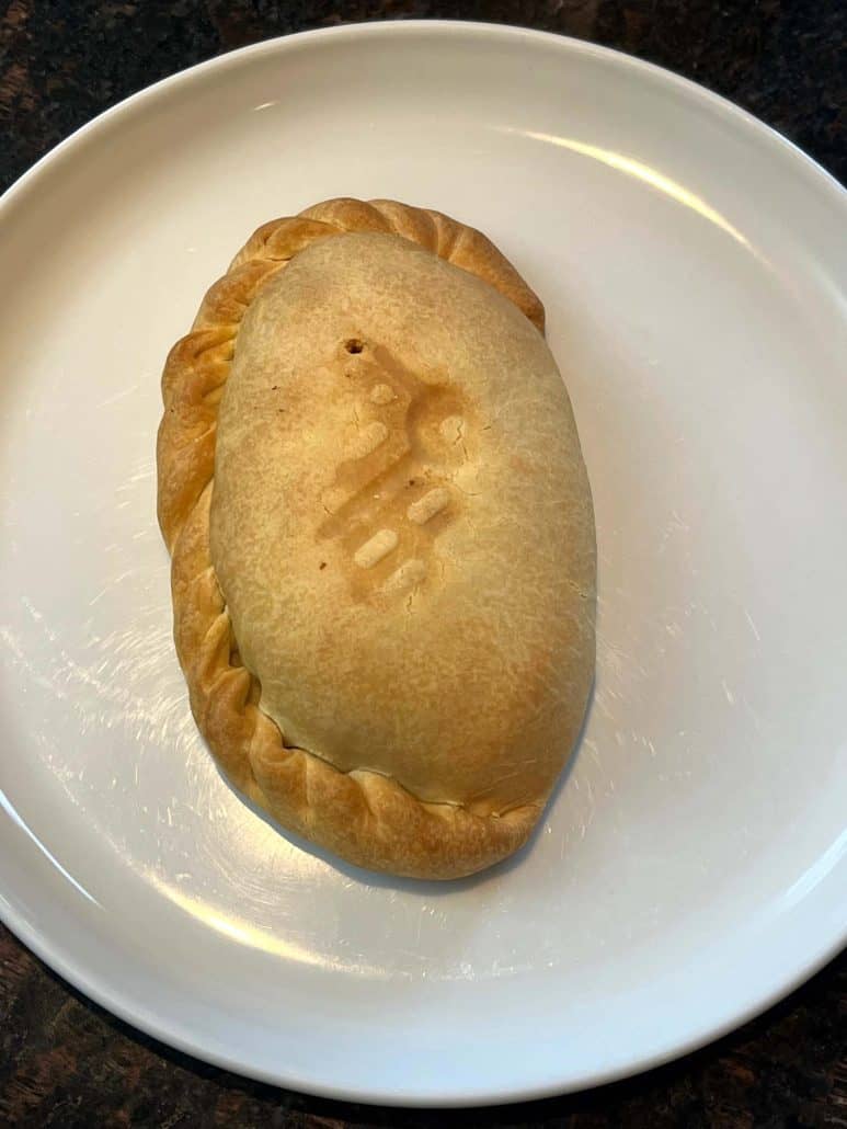 A freshly air-fried pasty on a white plate, showing its golden-brown crust.